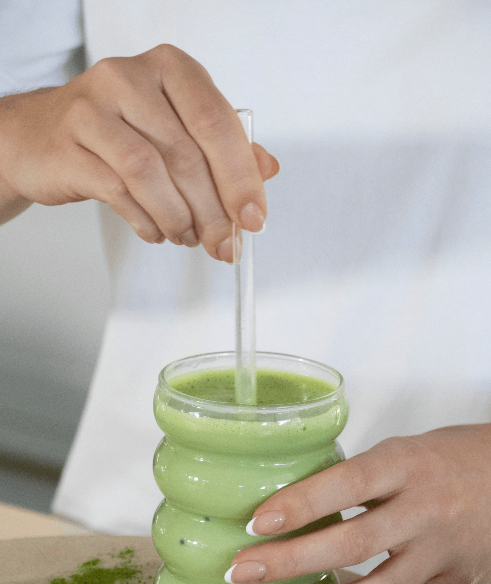Glass straw resting in a tall glass of iced matcha latte