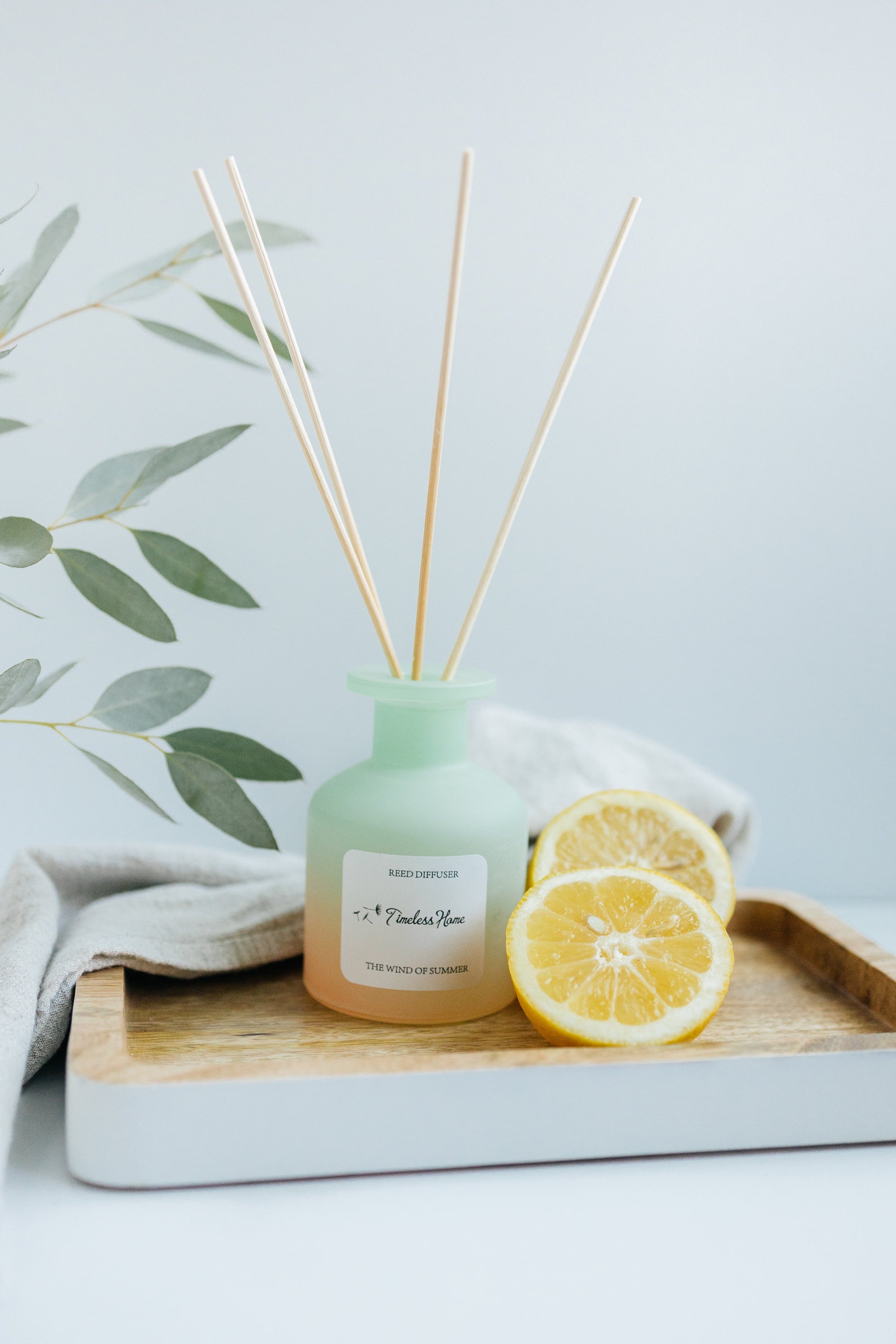 Reed diffuser styled beside folded linen on a dark surface