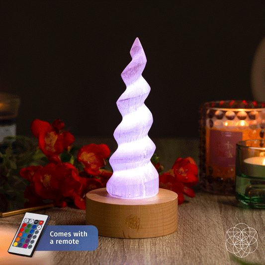 Handmade selenite flame lamp rising from a wooden base, lit in soft color
