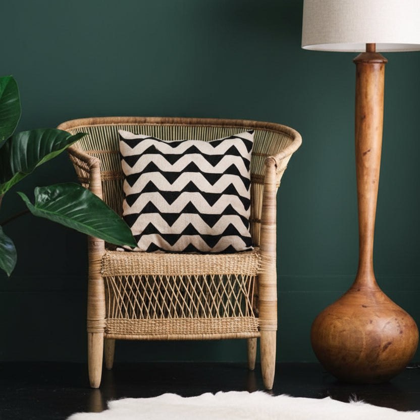 Malawi cane chair with a patterned cushion beside a wooden lamp in a green room
