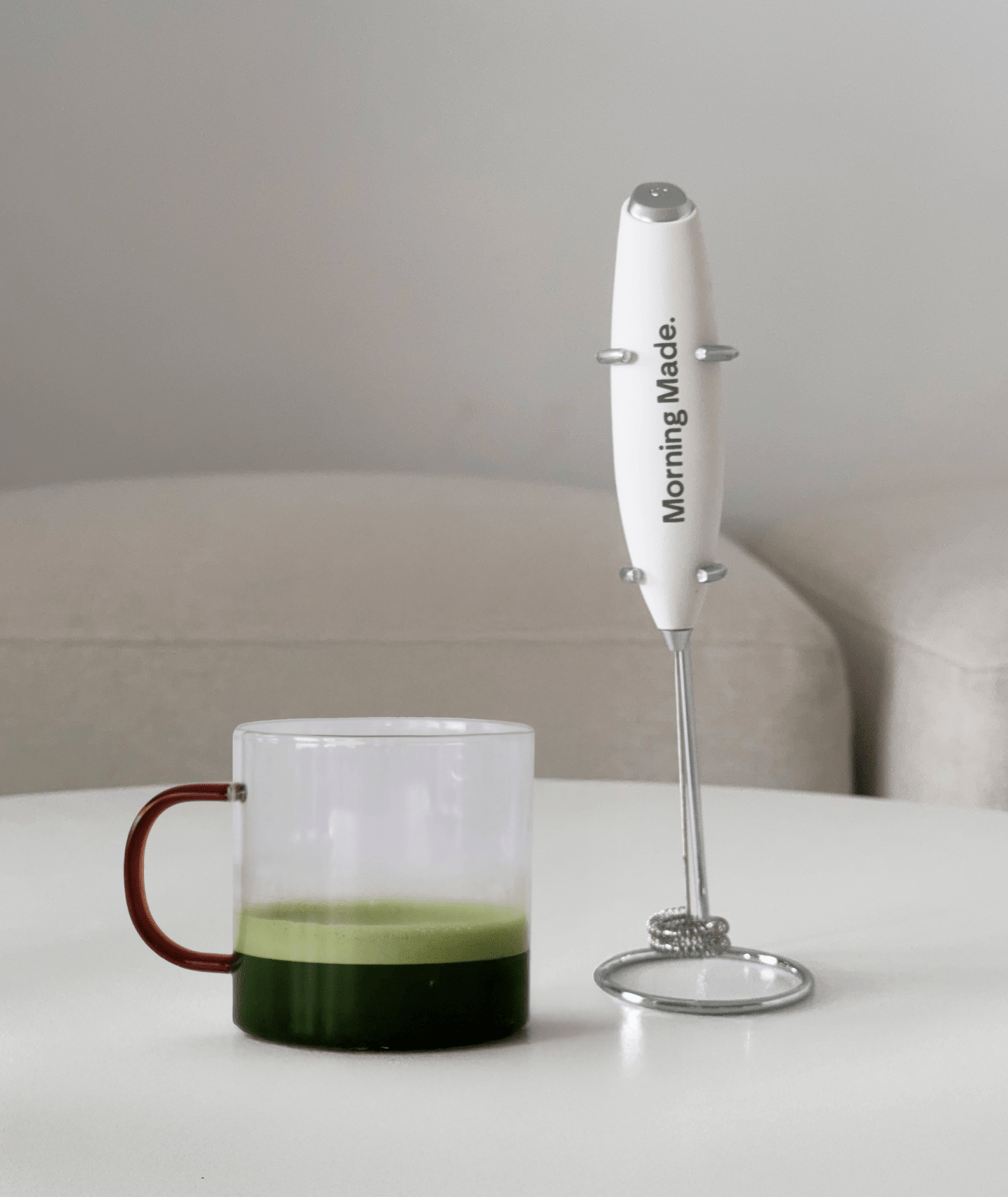 Electric matcha whisk frothing a green matcha latte in a glass