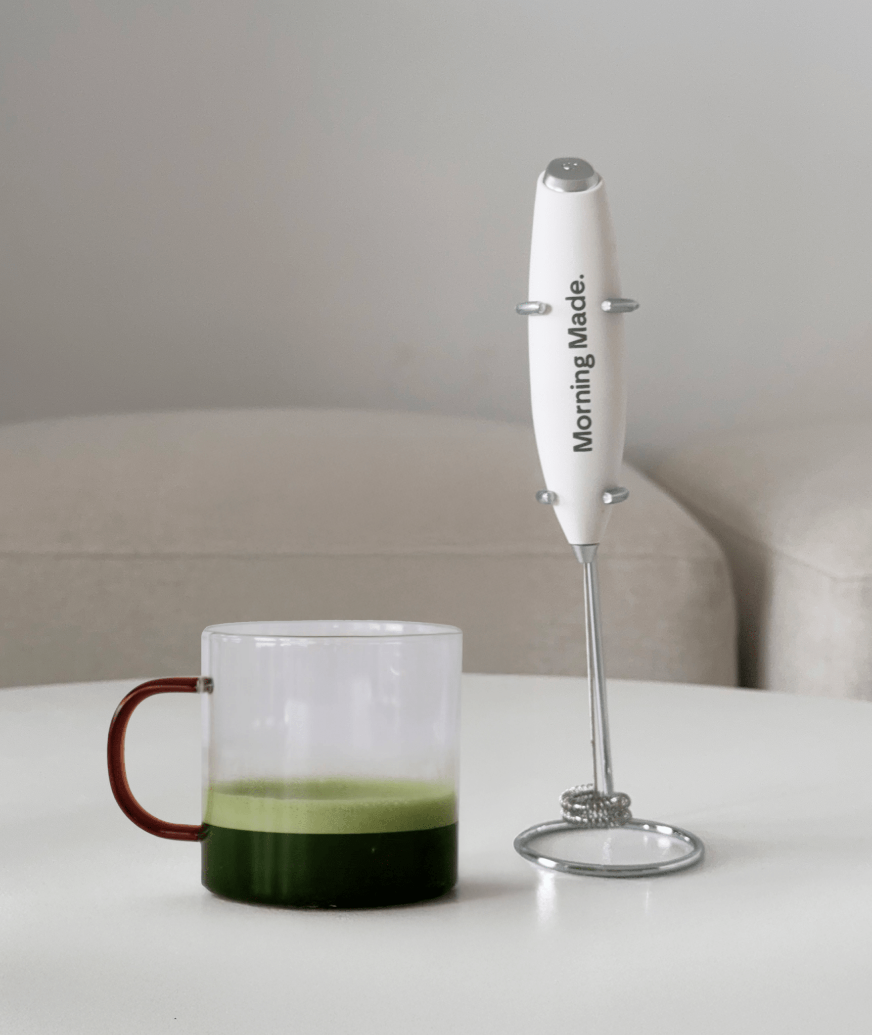 Electric matcha whisk frothing a green matcha latte in a glass