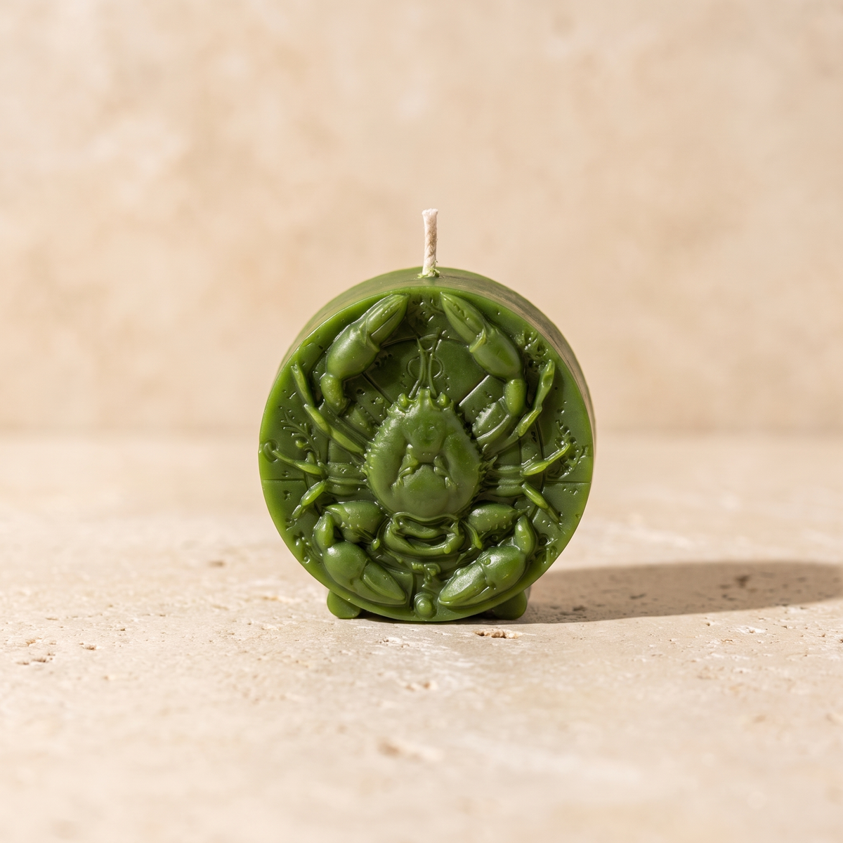Beeswax Cancer Crab zodiac spell candle in green, front view on a pale backdrop