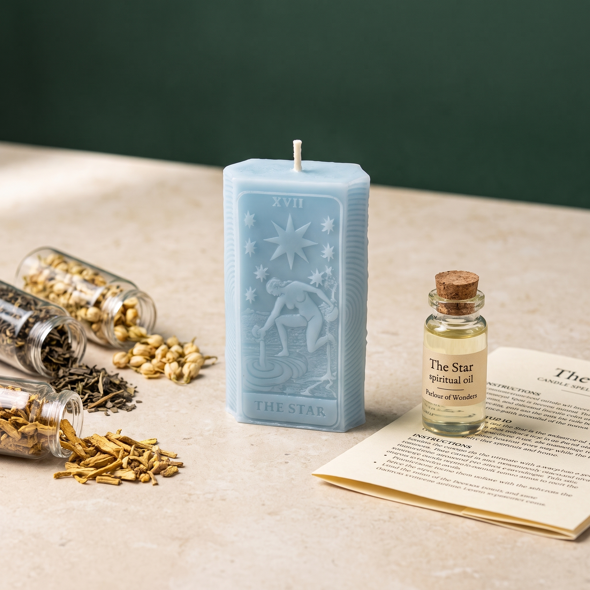 The Star candle spell kit laid out: a pale blue beeswax tarot-card candle beside jars of dried herbs, a corked bottle of dressing oil and the printed instruction sheet