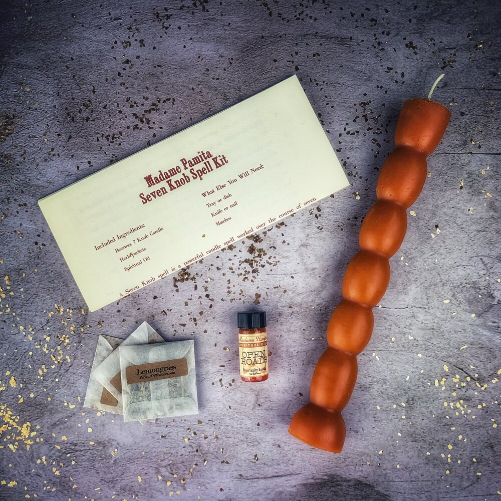 Contents of the Seven Knob Candle Spell Kit laid out: candle, three herbs and spiritual oil.