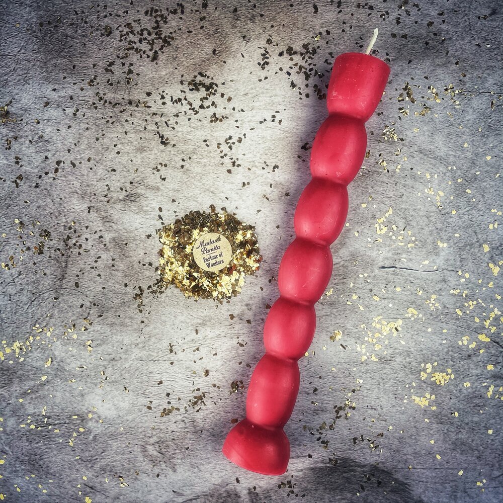 Red seven knob candle lying on gray stone, the flared base at the lower end.