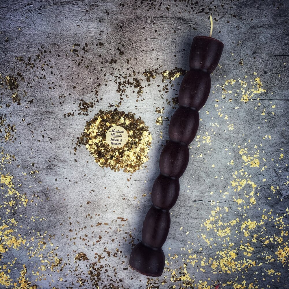 Dark plum seven knob candle on gray stone, the seven knobs evenly stacked to the flared foot.