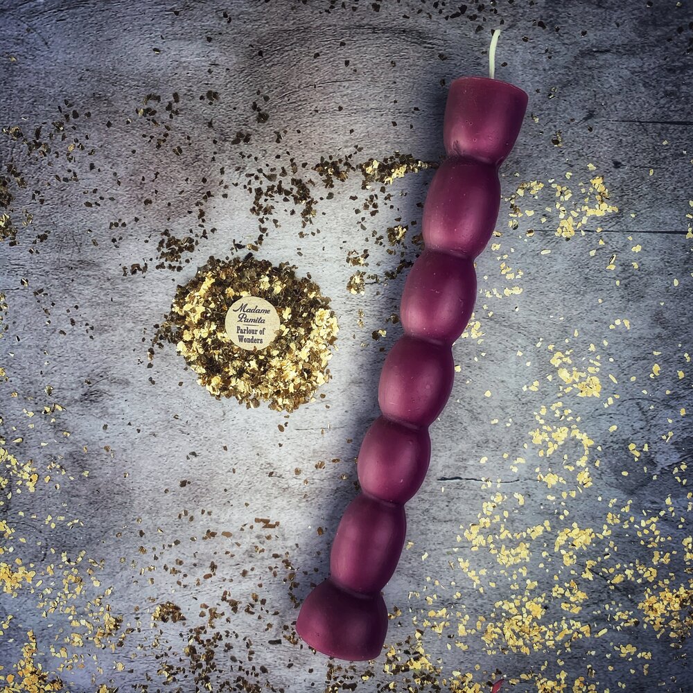 Magenta seven knob candle on gray stone, each knob catching a highlight.