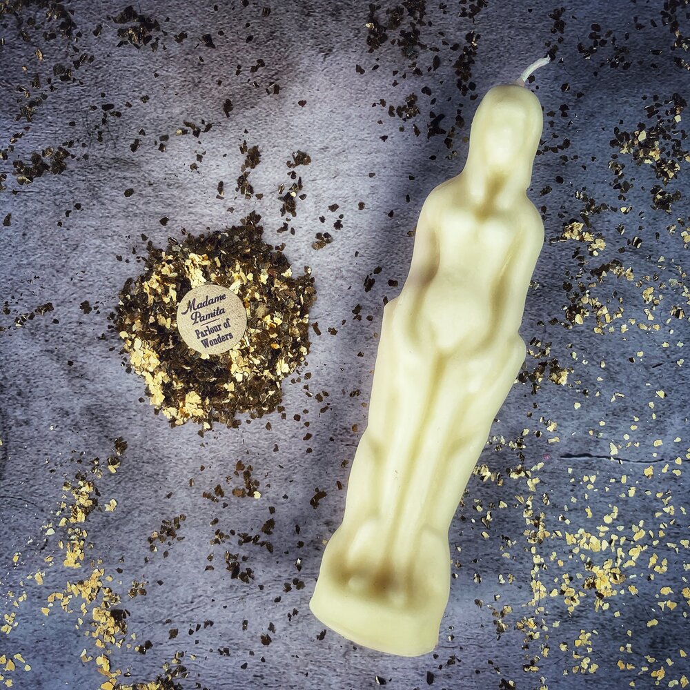 Cream white beeswax female figure candle on gray cloth flecked with gold