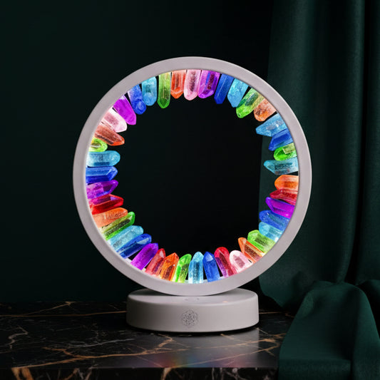 Ring lamp set with rainbow-colored quartz points, lit on black marble against a dark green curtain
