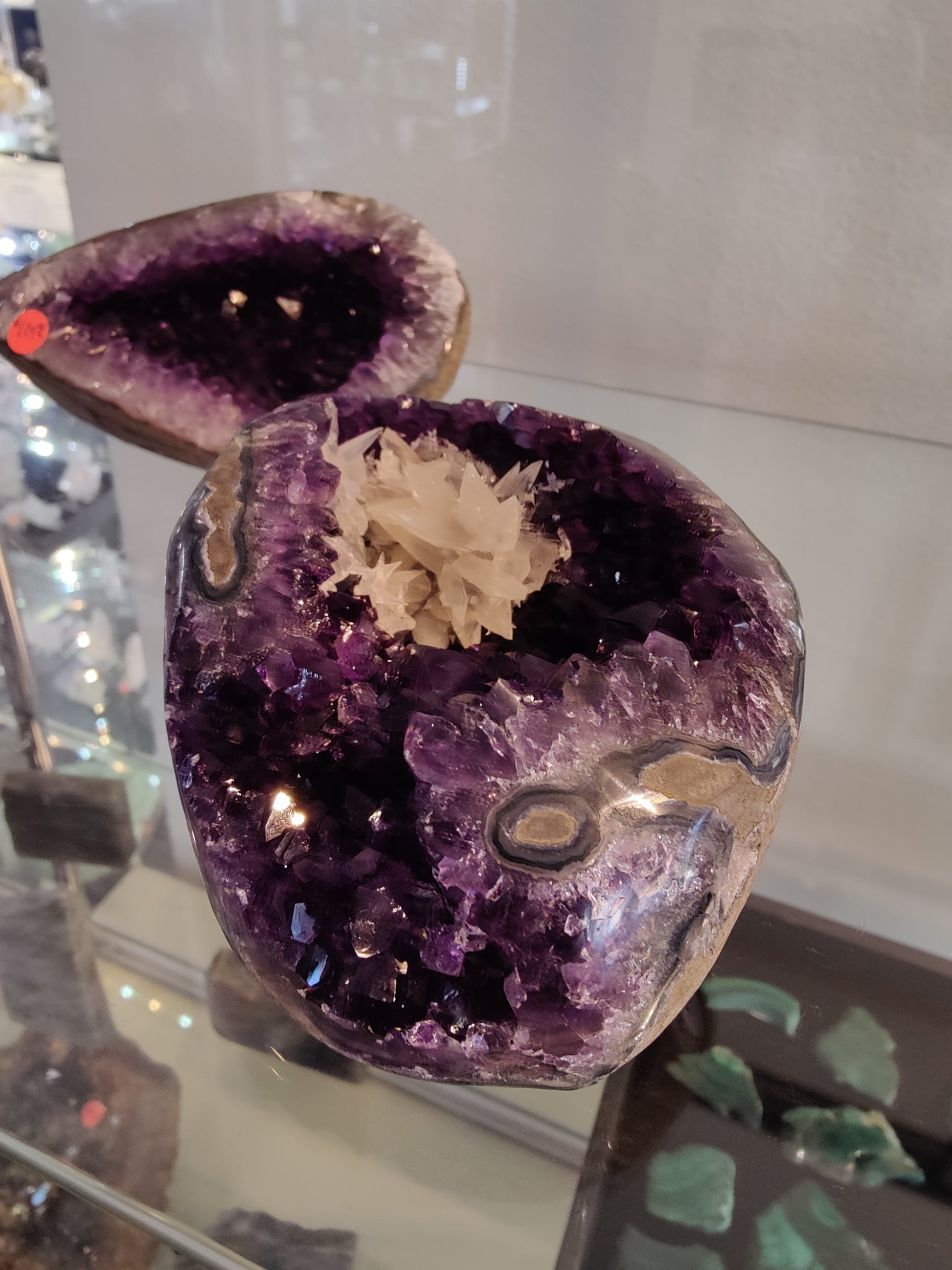 Polished-edge amethyst geode from Brazil with a white scalenohedral dogtooth calcite cluster growing inside the purple crystal bed — view 2
