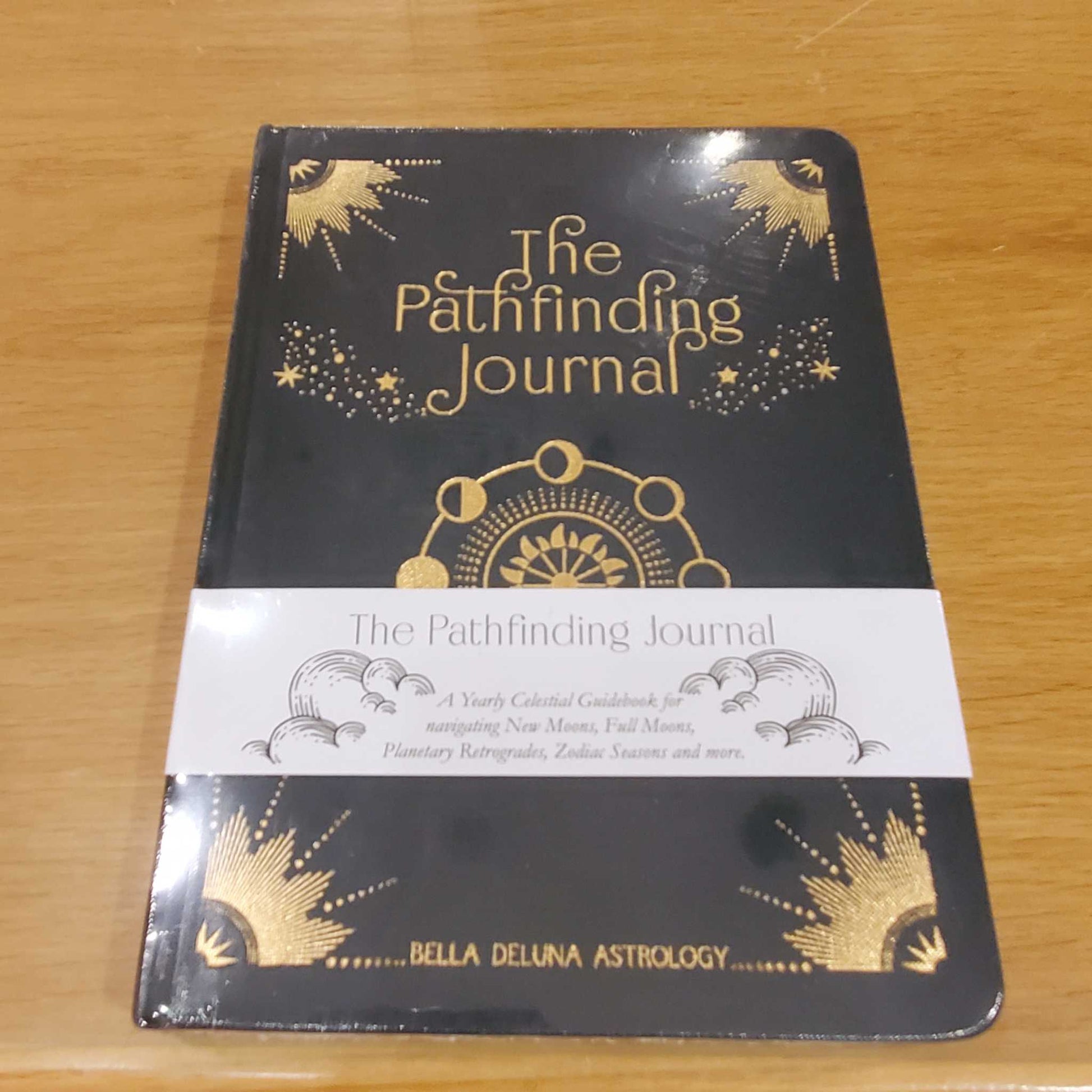 Hardcover copy of The Pathfinding Journal, dark navy with gold celestial artwork, from Bella de Luna Astrology