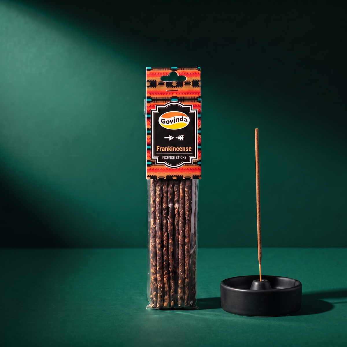 The Govinda Frankincense packet beside a black ceramic incense dish with a single stick set upright in it