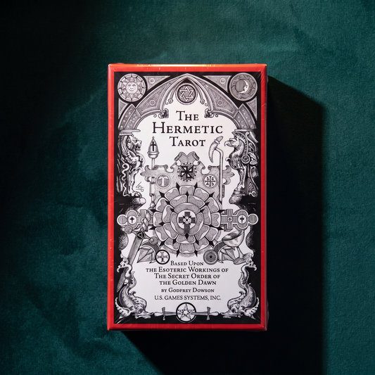 The Hermetic Tarot box upright on deep green velvet with a hard diagonal shadow falling across the fabric