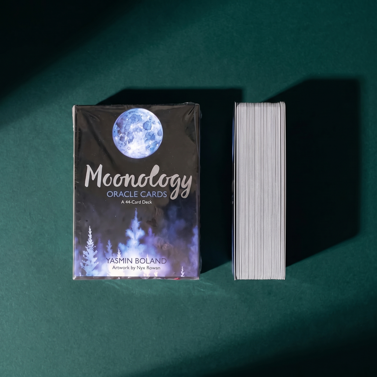 The shrink-wrapped Moonology Oracle Cards box next to the card block on its side, showing the deck's thickness
