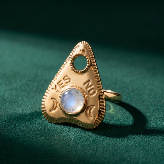 Gold vermeil planchette ring set with a rainbow moonstone cabochon, standing upright on green velvet
