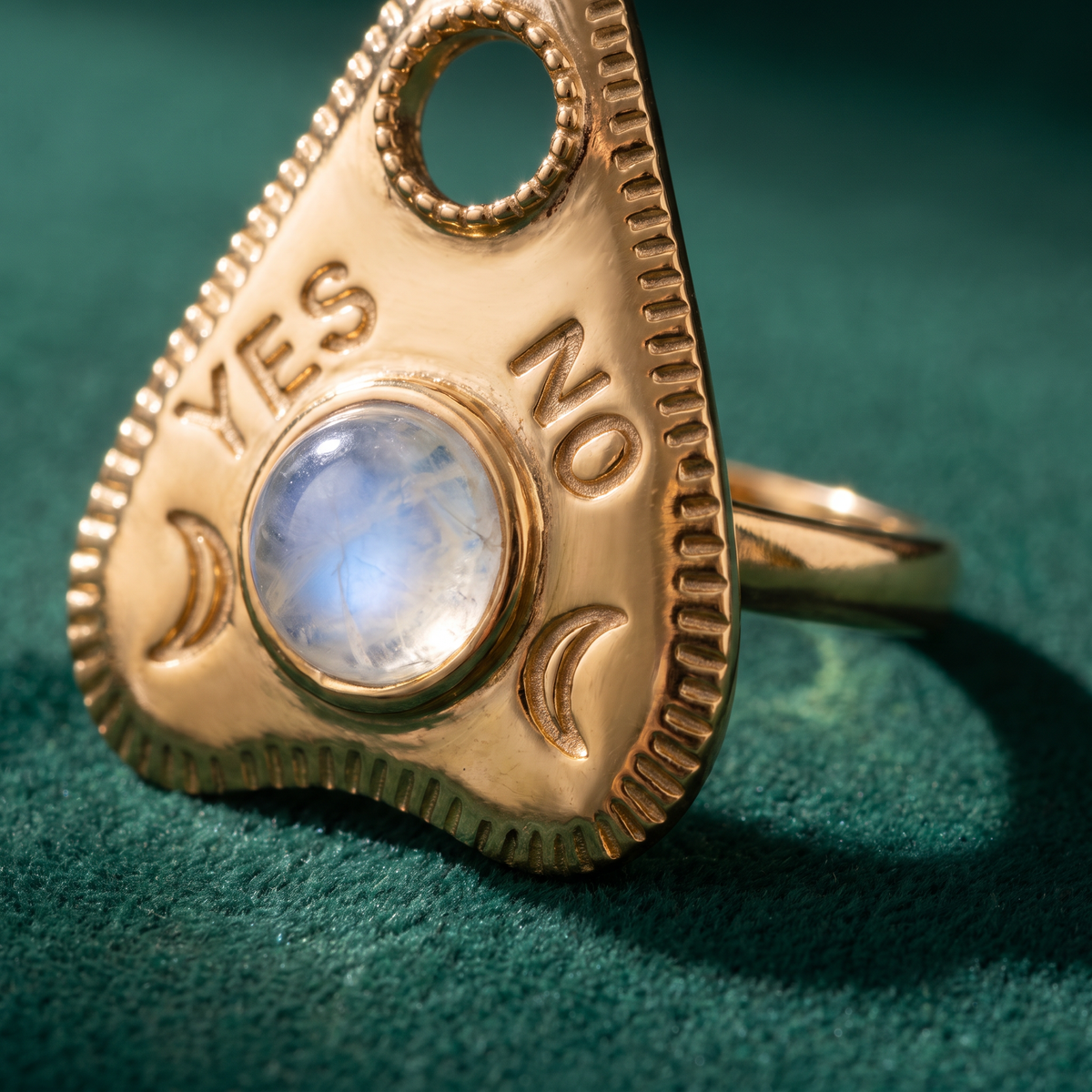 Close view of the gold vermeil planchette ring: YES and NO engraved either side of the moonstone, crescent moons below and a milled edge all round