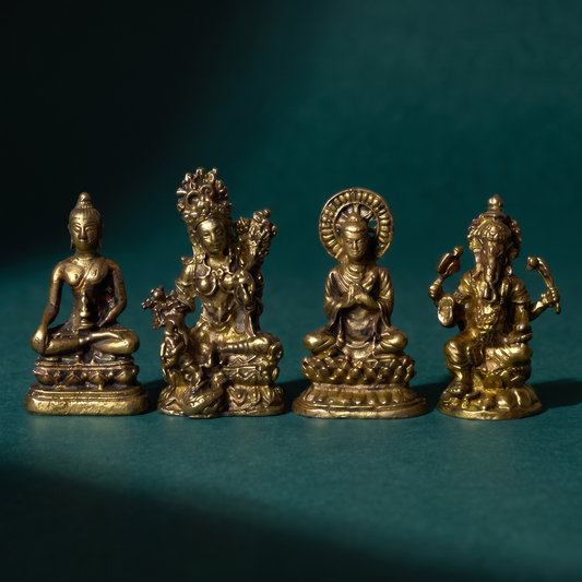 Close view of four miniature brass figures on dark green velvet, showing the cast detail in the faces and halos