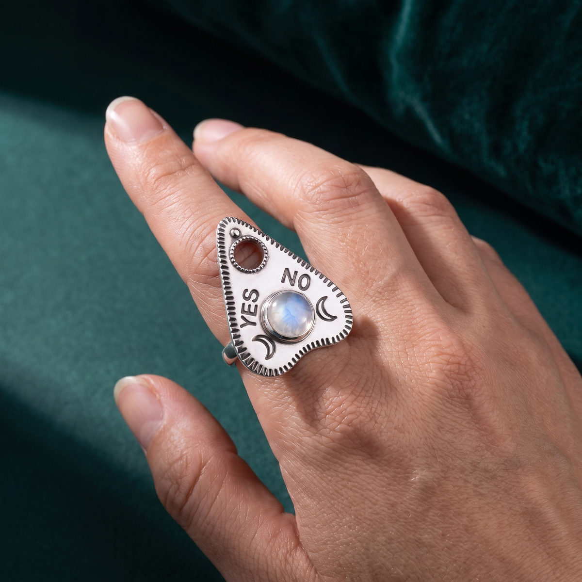 The planchette ring worn on a finger, showing how the pointed silver face sits across the knuckle