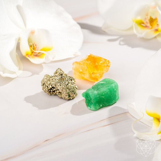 Three raw abundance stones — golden Citrine, metallic Pyrite, and green Aventurine