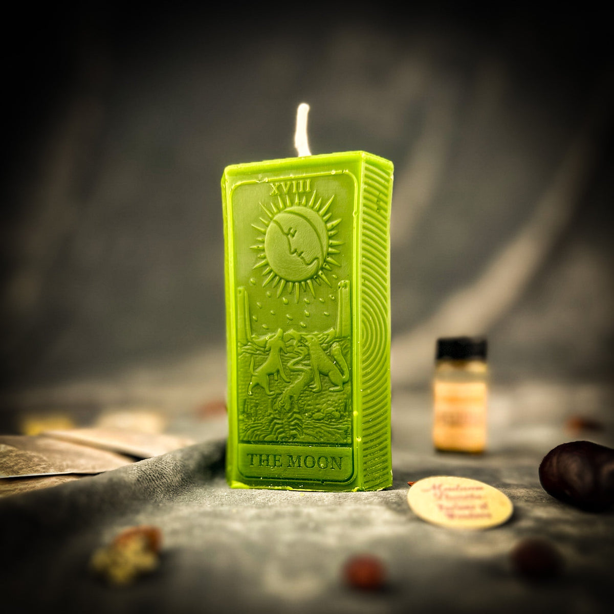 Olive green beeswax The Moon tarot card candle with a vial of dressing oil and the kit contents behind it