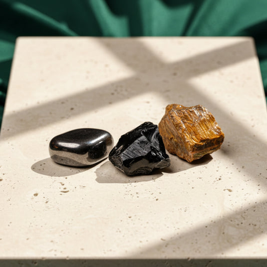 Hematite, black obsidian and tiger's eye on a pale stone slab in slanting sunlight