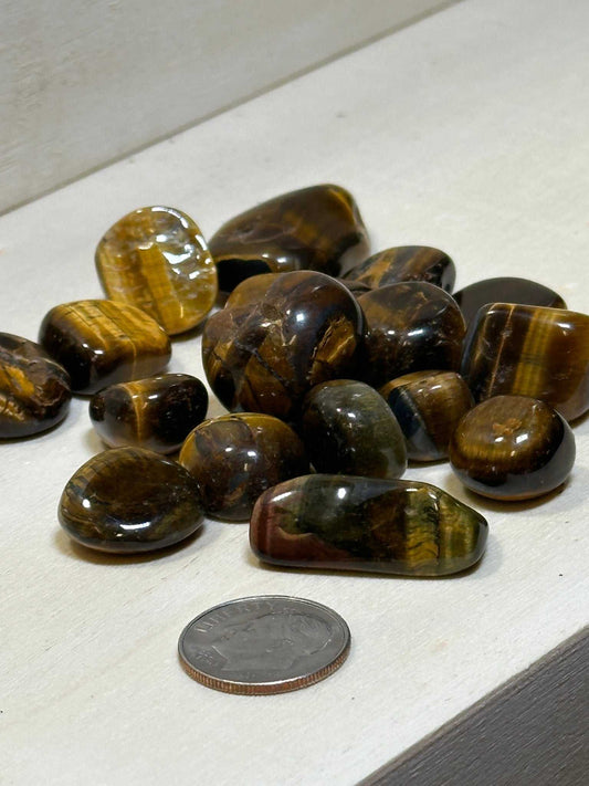 Bag of tumbled tiger eye pebbles with golden-brown chatoyant banding