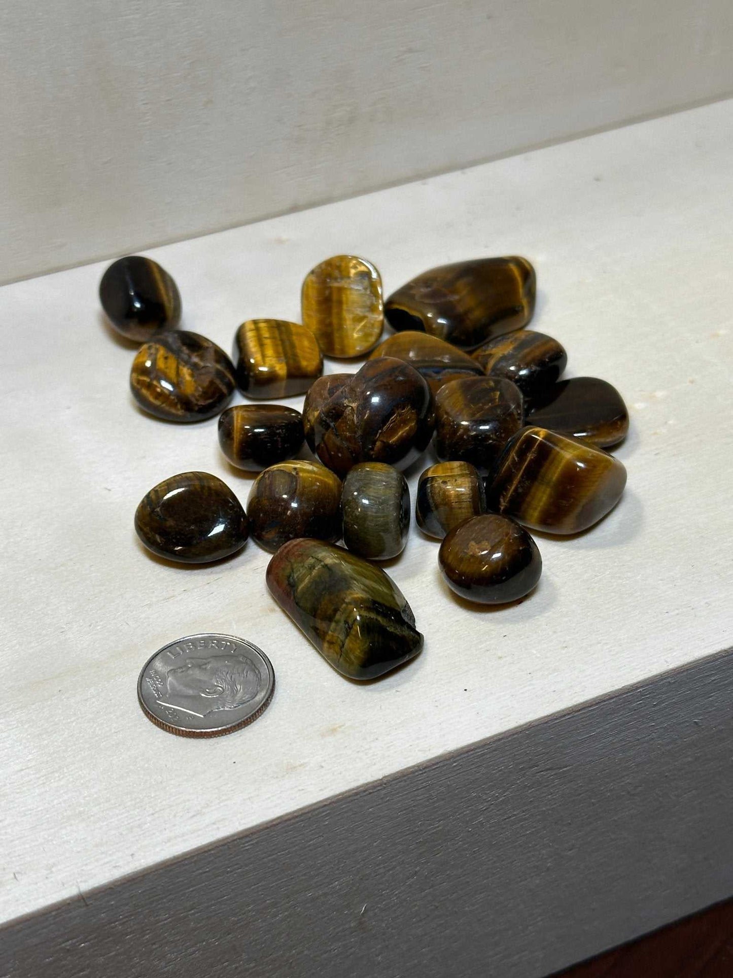 Bag of tumbled tiger eye pebbles with golden-brown chatoyant banding — close-up view