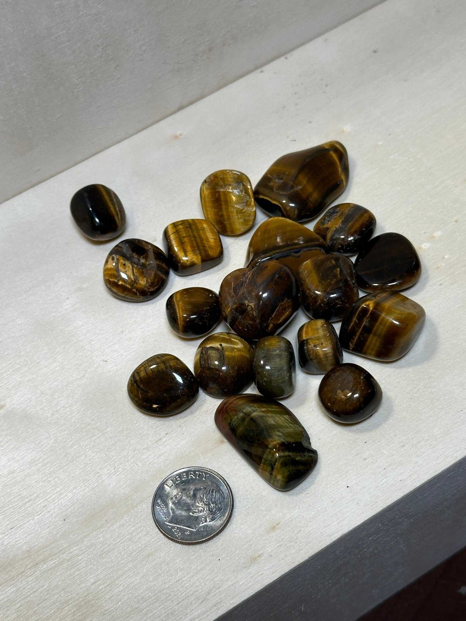 Bag of tumbled tiger eye pebbles with golden-brown chatoyant banding — shown from a second angle