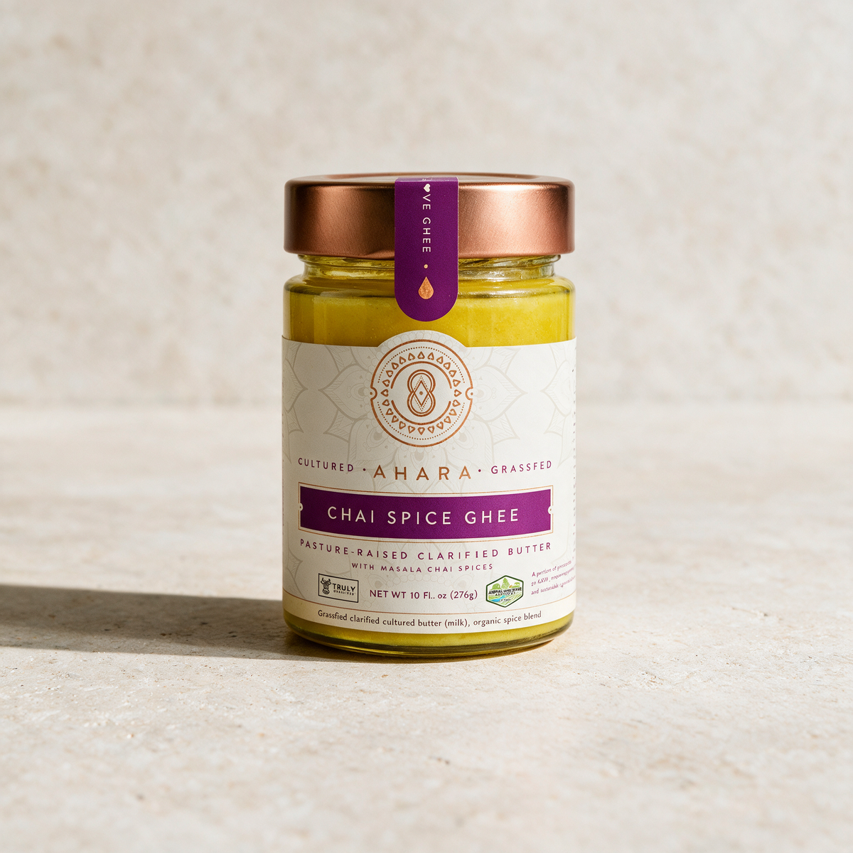 Ahara Rasa Chai Spice ghee in the 10 fl oz jar with a copper lid and magenta label on pale stone