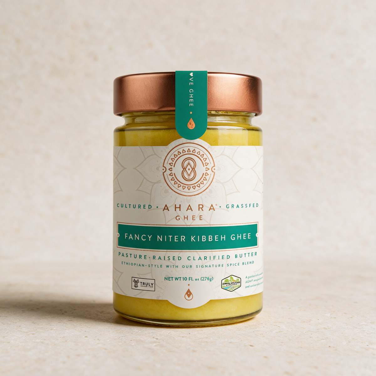 Ahara Rasa Fancy Niter Kibbeh ghee in the 10 fl oz jar with a copper lid and teal label, standing on pale stone