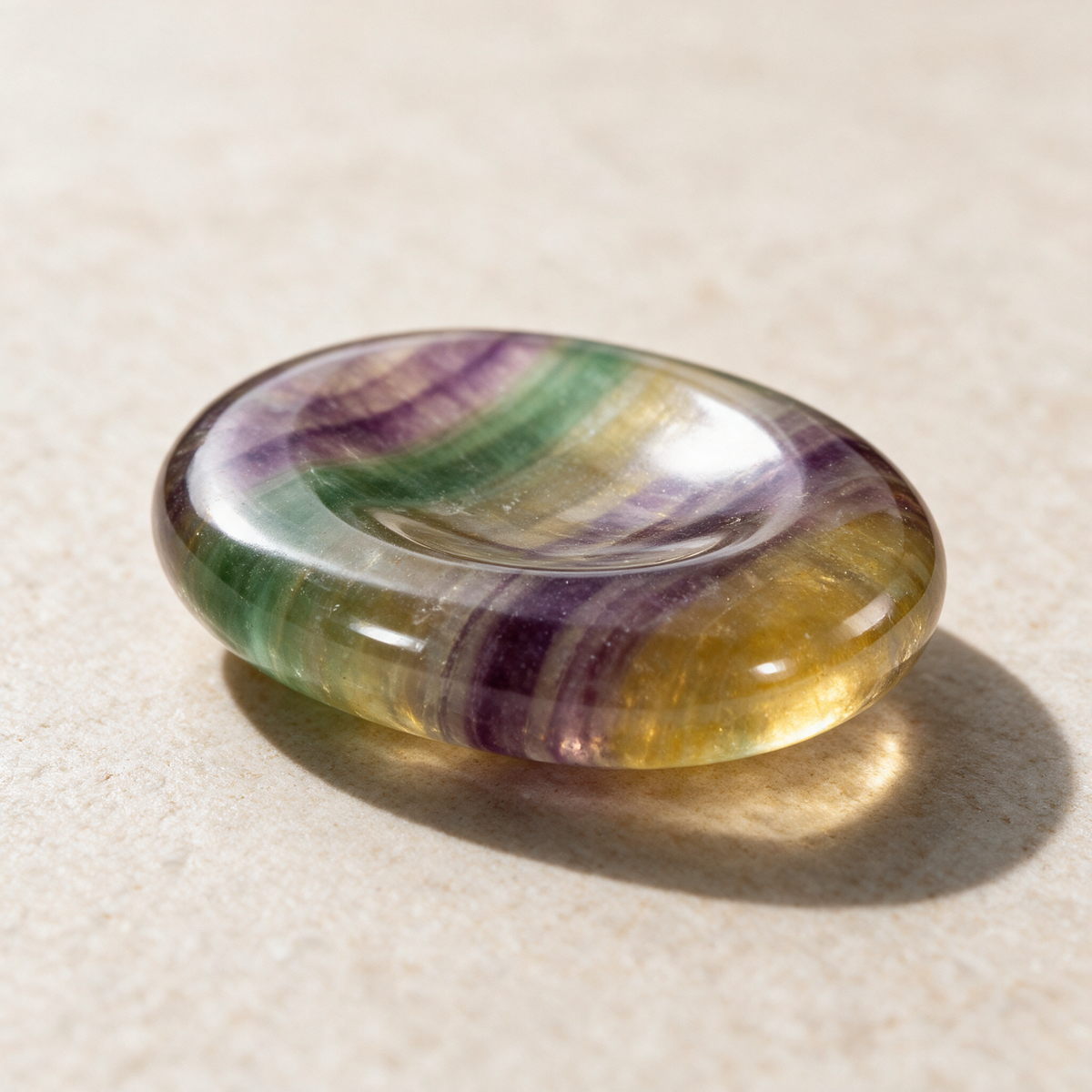 The same fluorite comfort stone lit from the side, the color bands running the length of the oval