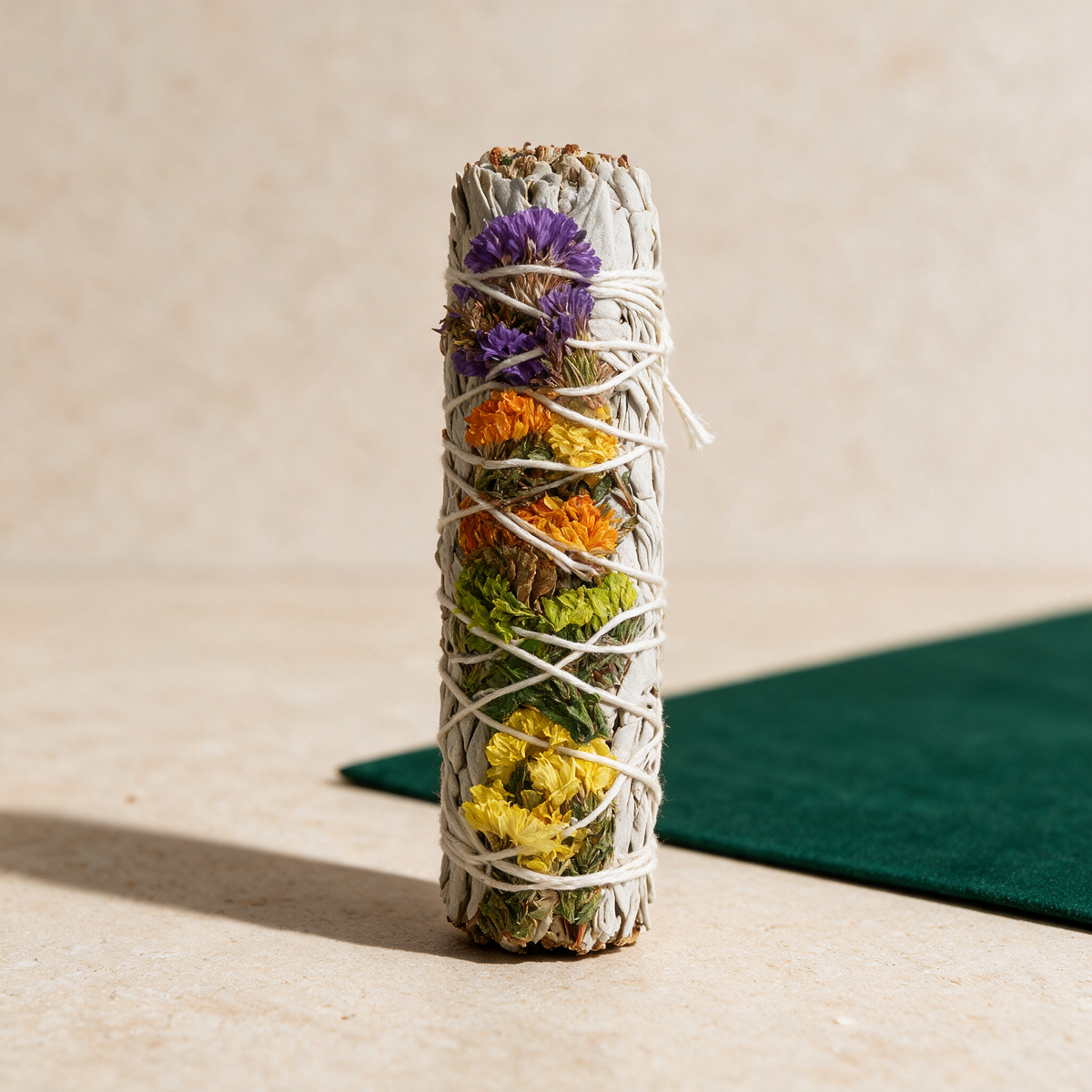 The bundle standing on end against dark green cloth, so its full length and the band of purple, yellow and orange flowers are visible.
