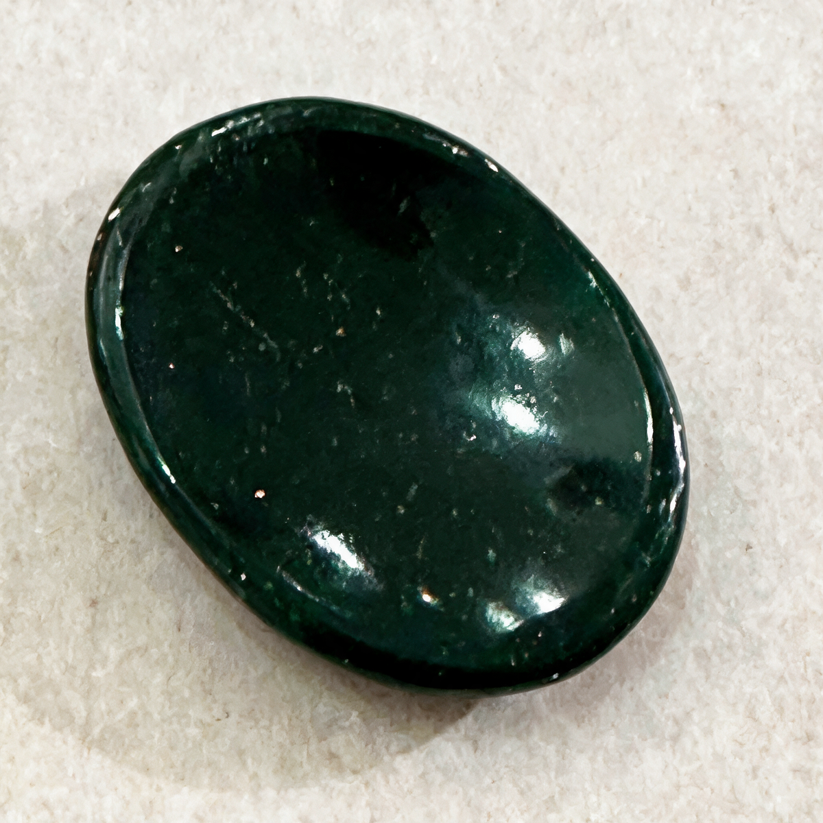 Close view of the green goldstone comfort stone on white, showing the smooth domed profile