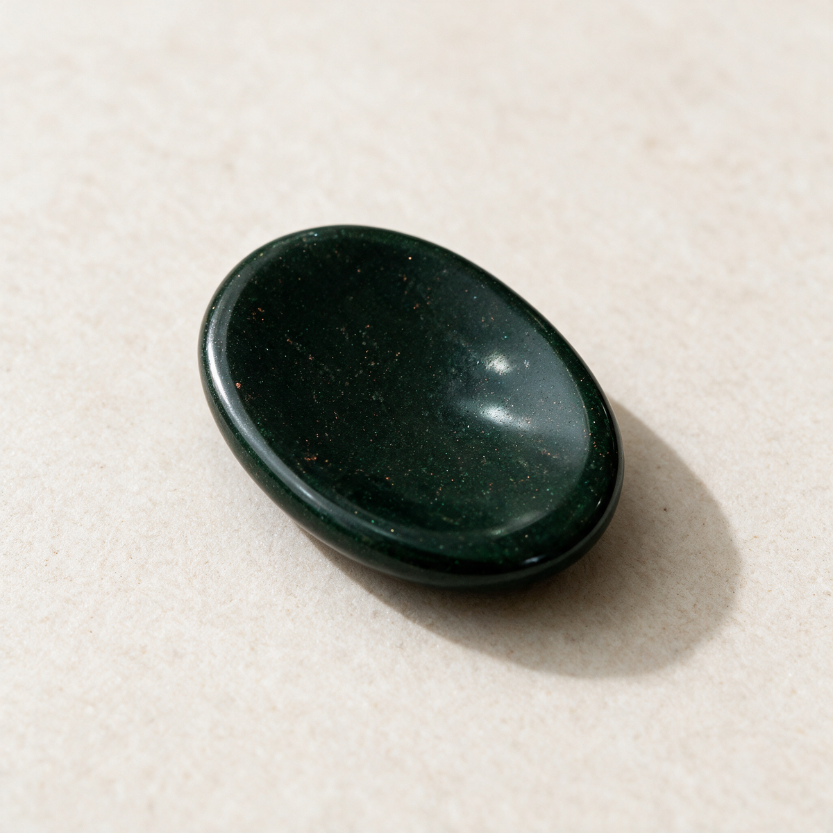 The same green goldstone comfort stone from above, its glossy oval face reflecting the light