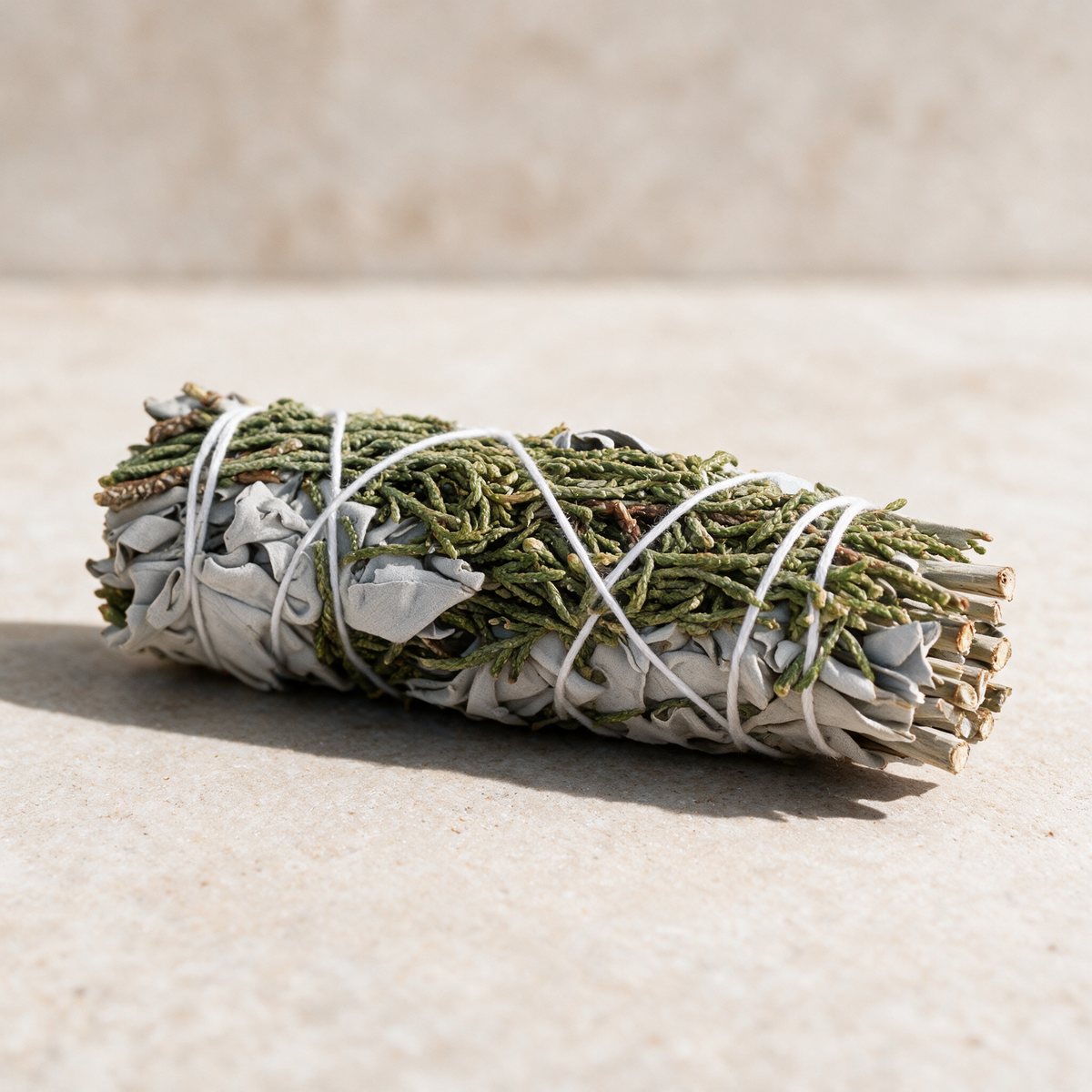 Close view of juniper sprigs and silvery white sage leaves wound with white cotton string