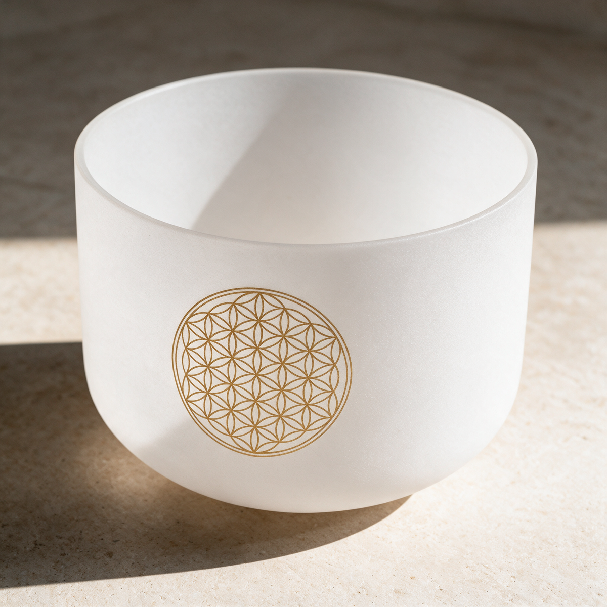 16-inch white frosted crystal singing bowl on a cream rug, gold Flower of Life design on the outside wall