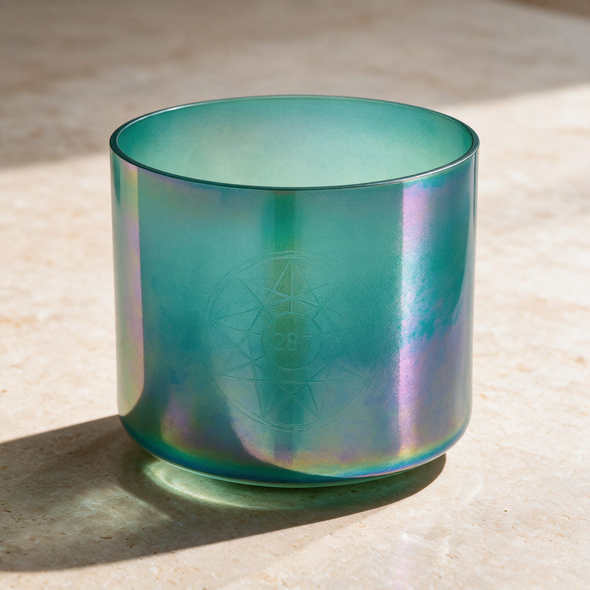 The 6.75-inch turquoise-green singing bowl on a pale stone surface, its iridescent sheen catching the light.