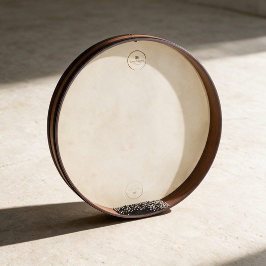 22-inch ocean drum standing upright on a pale surface in daylight, steel beads pooled along the lower edge of the head