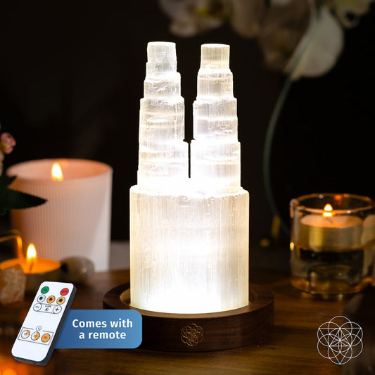 Two carved Selenite towers glowing side by side on a wooden base