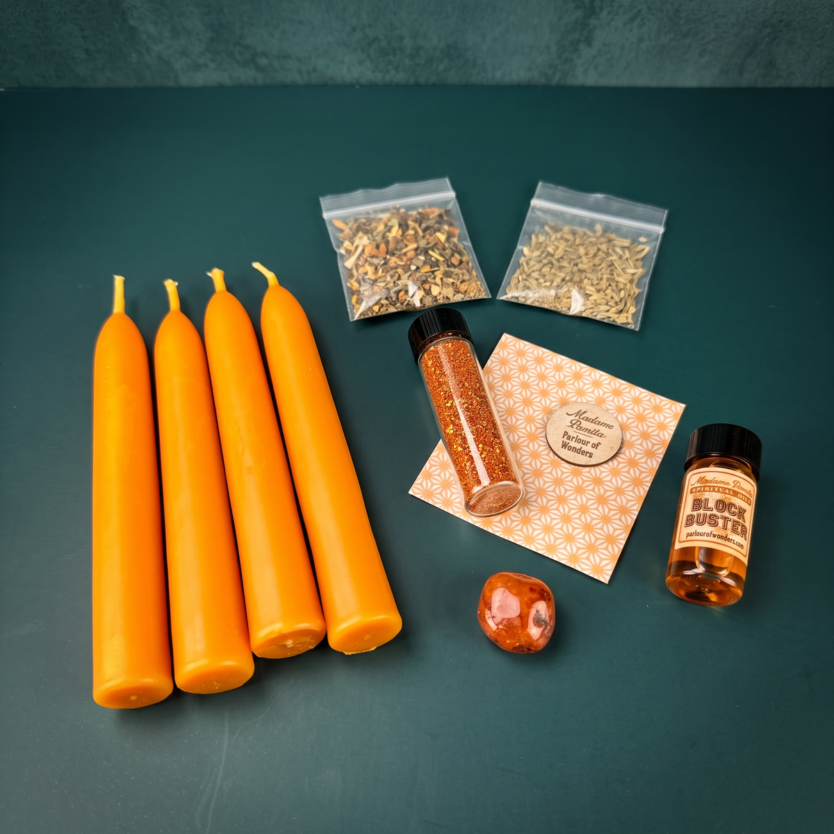 Breakthroughs Candle Spell Booster Pack with four orange beeswax taper candles, Block Buster oil, herb packets, glitter and a crystal on a teal backdrop