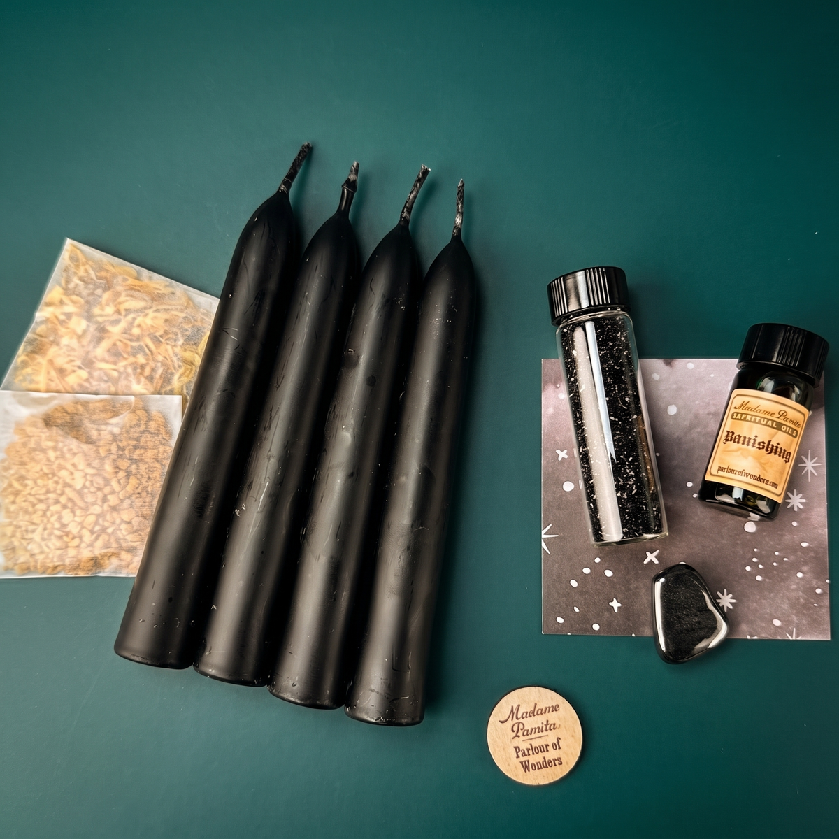 Banishing Candle Spell Booster Pack with four black beeswax taper candles, Banishing oil, herbs, a tumbled gemstone and glass glitter