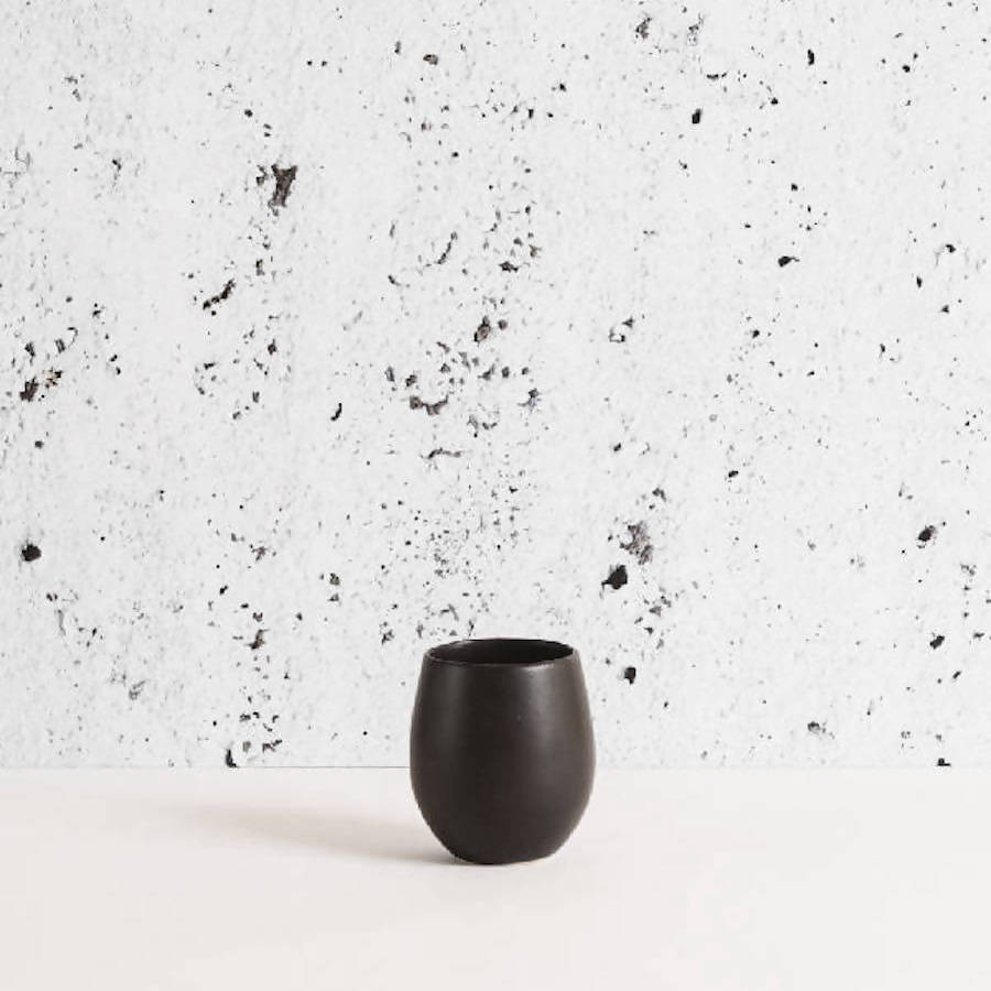 Black Epa stoneware cup against speckled plaster